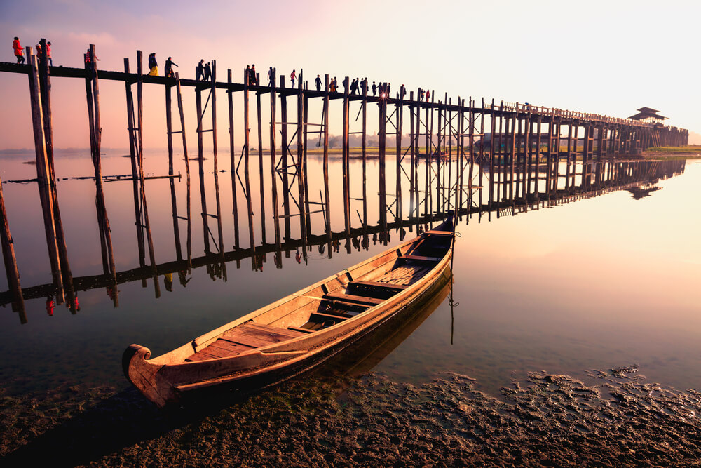 People traveling across the U Bein Bridge in the evening. Mandalay Myanmar with sunset